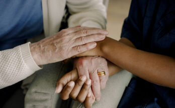 Midsection of senior woman and female healthcare worker with hands stacked at retirement home