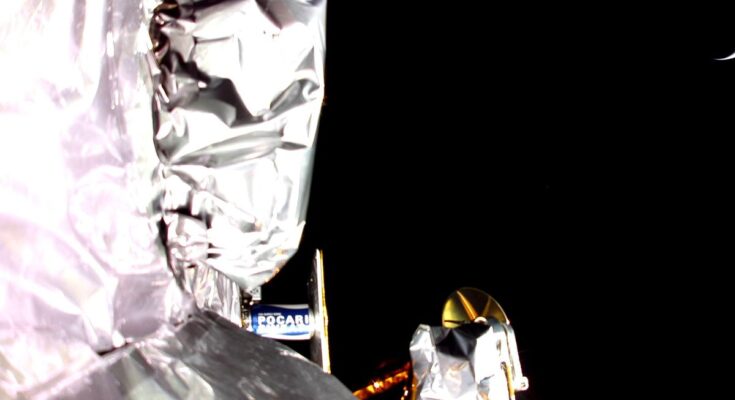 photo showing the silvery insulation of a spacecraft and the blackness of space in the background, with a possible sliver of earth in the upper right corner.