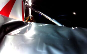 crumpled silver-colored foil can be seen in the foreground. behind it a metal strut with a bend in it can be seen. the empty blackness of space fills the background of the image