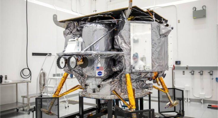 a silver spacecraft sits in a large white-walled room.