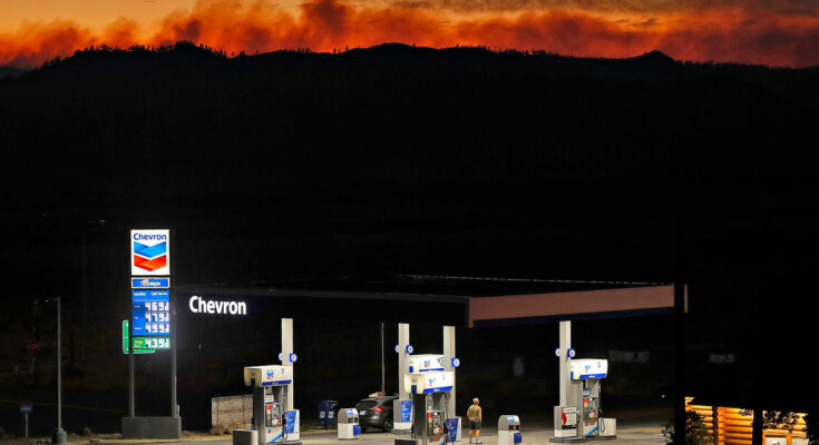 Photo of a Chevron gas station lit up at night in front of an orange, fiery sky