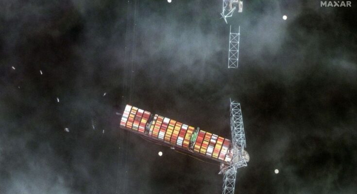 a collapsed bridge with a large container ship underneath it