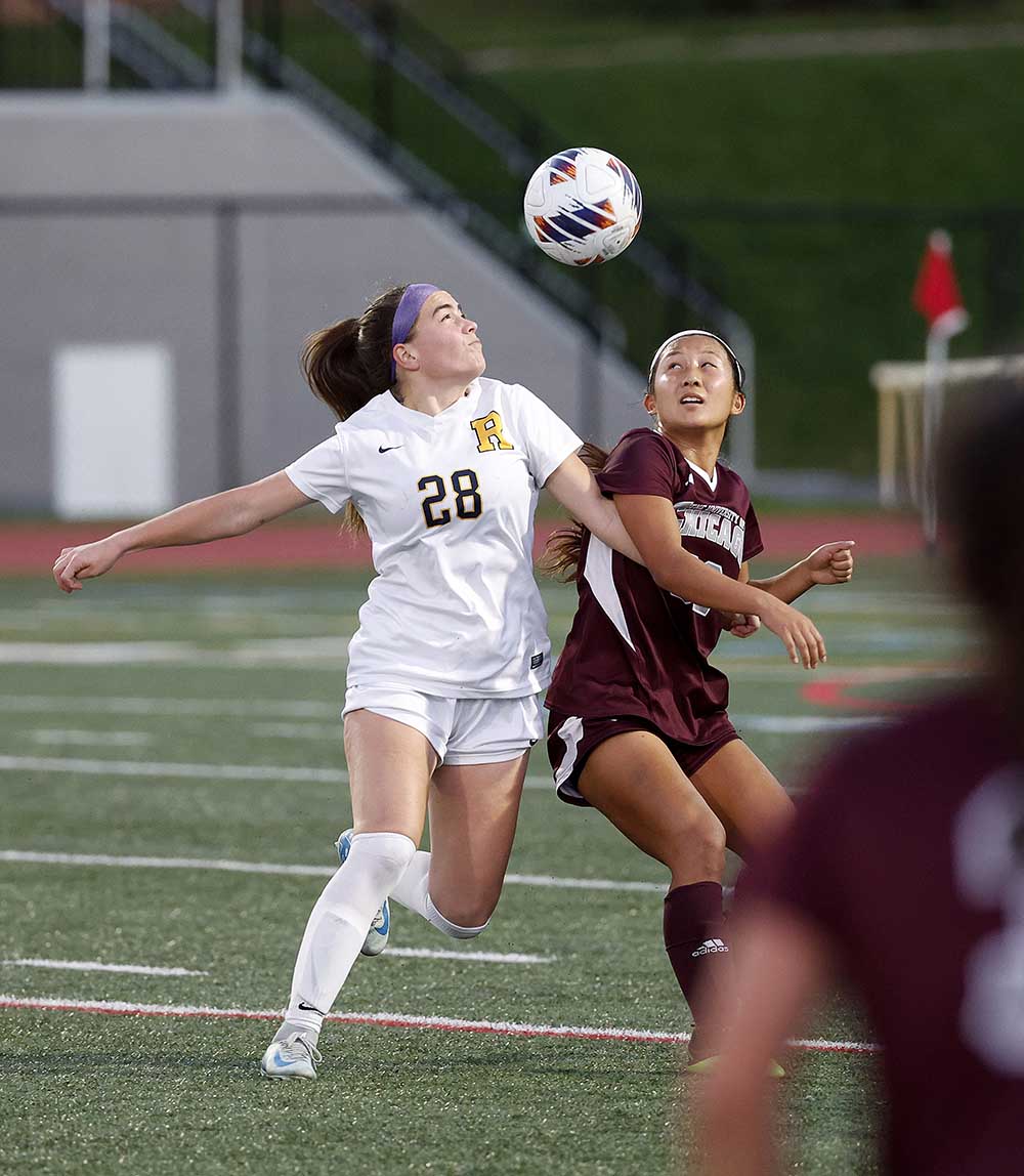 El drama de fútbol femenino de la Universidad de Rochester se dirige al balón con miembros del equipo rival más cercano.