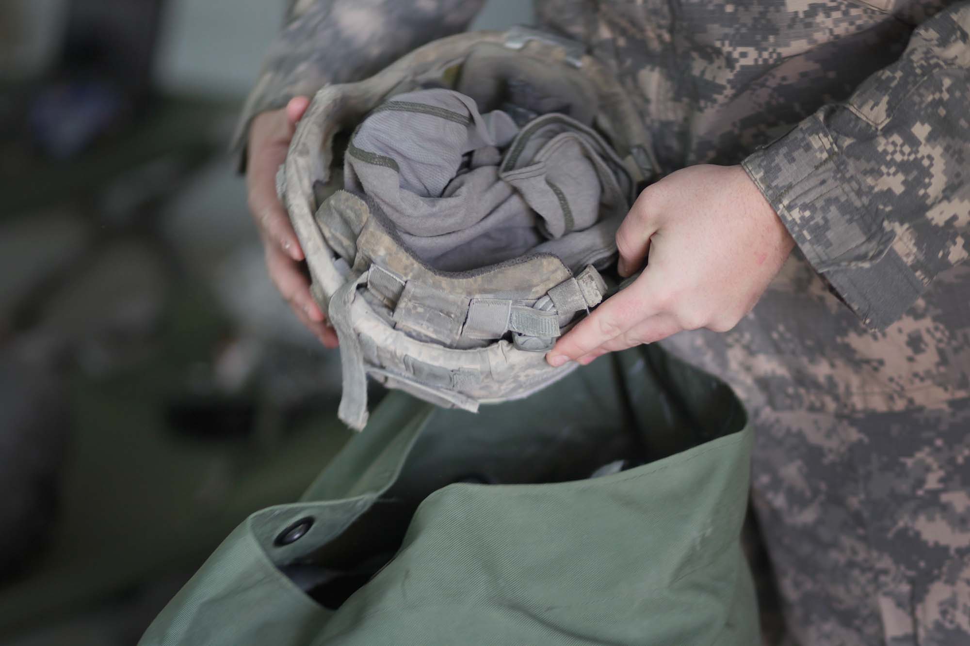 Las manos del soldado del Ejército de EE. UU. Sostienen un casco cerca de las manos abiertas Ruxac. 
