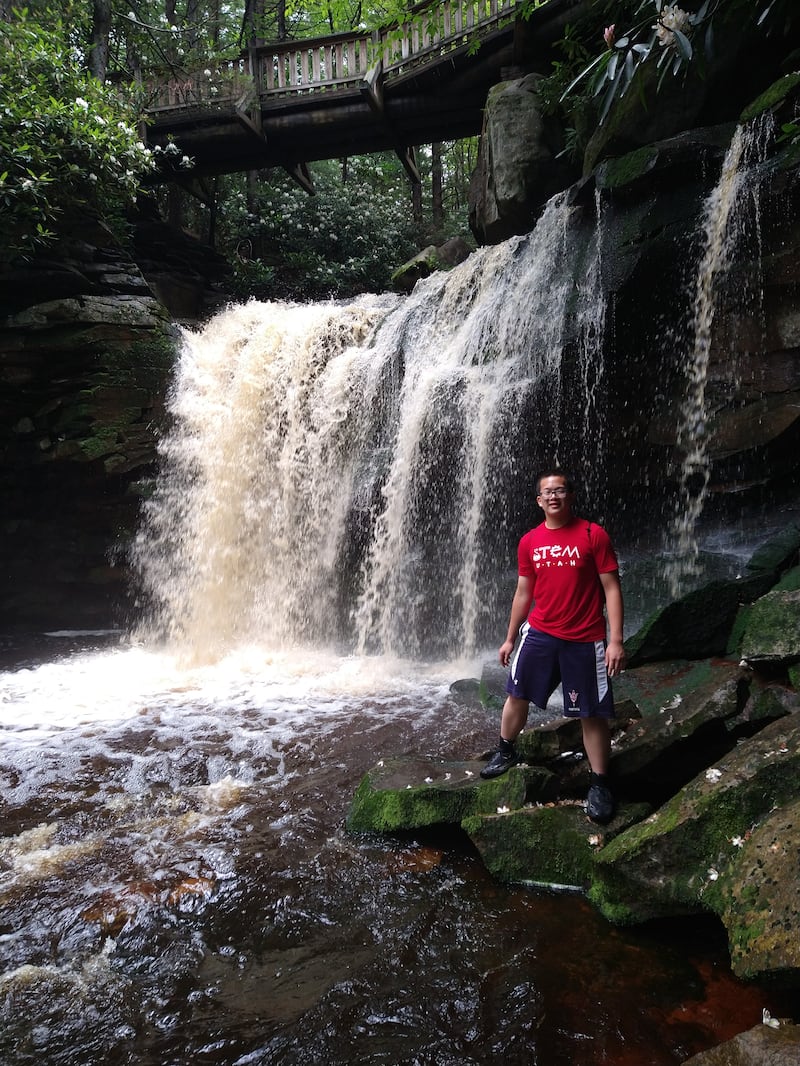 El 20 de julio de 2025, Benjamin Chiu sonrió junto a la cascada en el Bosque Nacional de Monongaela, Virginia Occidental, mientras estaba en el Campamento Nacional de Ciencias Juveniles.