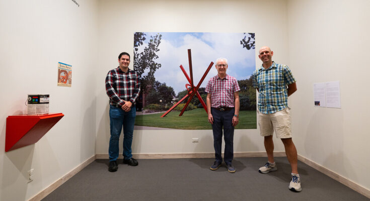 Tres investigadores parados en la exposición del Museo de Arte de Sheldon