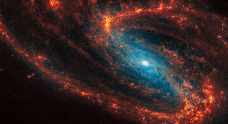 A photo of a spiral galaxy with orange arms and a glowing blue center