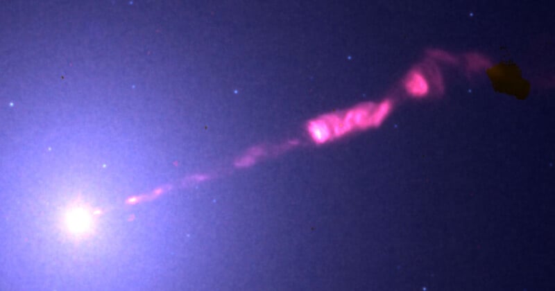 El material del cielo brillante emite un chorro rosa brillante y brillante que se extiende diagonalmente a través del espacio, rodeado de tenues estrellas contra el fondo oscuro.