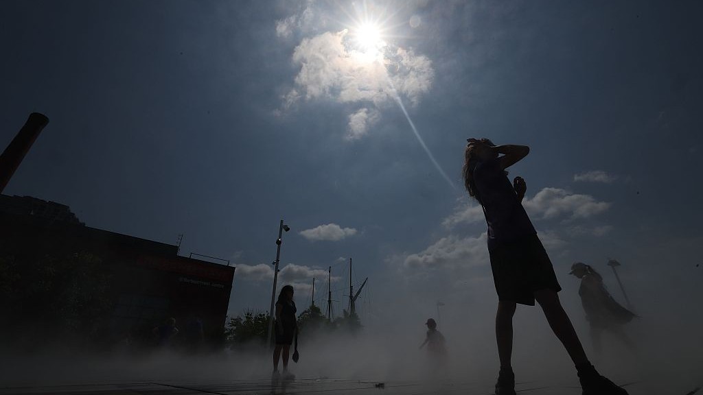 La gente se refresca bajo el sol en una plataforma de enfriamiento en Toronto.