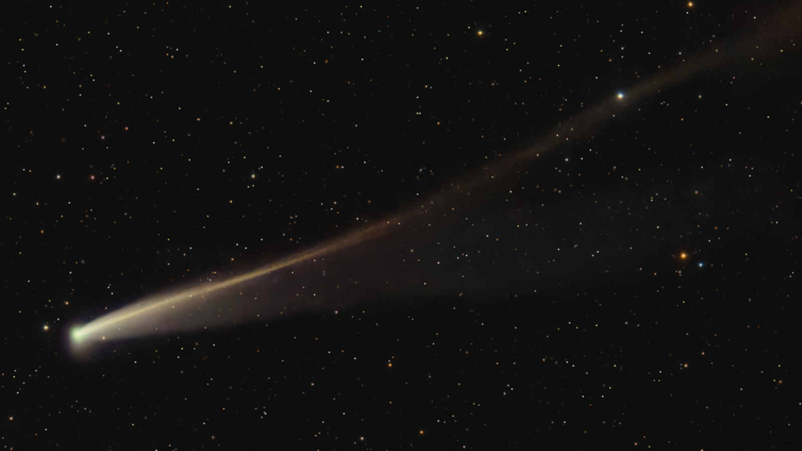 Foto de un cometa dorado con una cola larga y ondulada en el cielo nocturno.