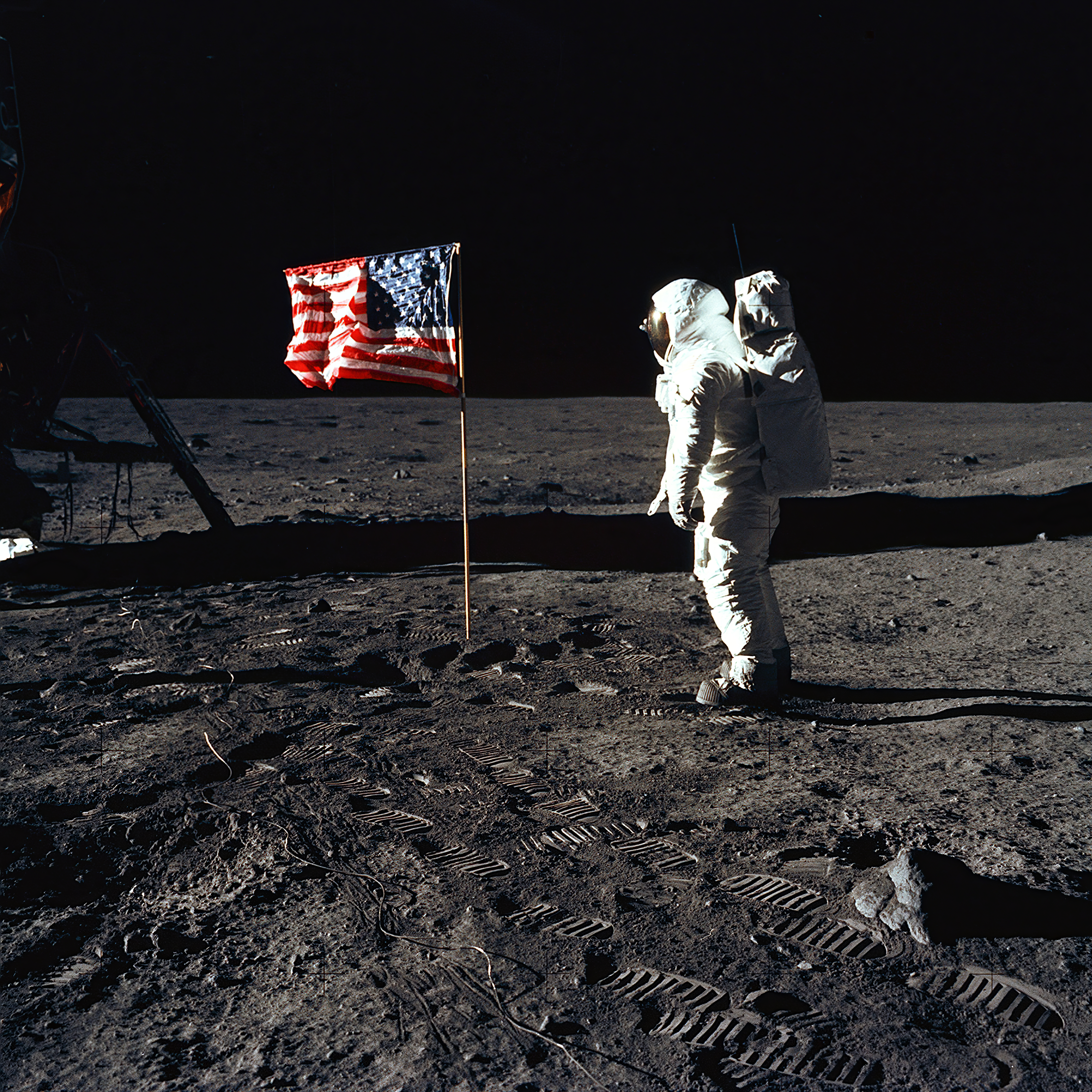 El astronauta Buzz Aldrin se encuentra en la Luna junto a una bandera estadounidense, con el módulo lunar y sus huellas visibles.