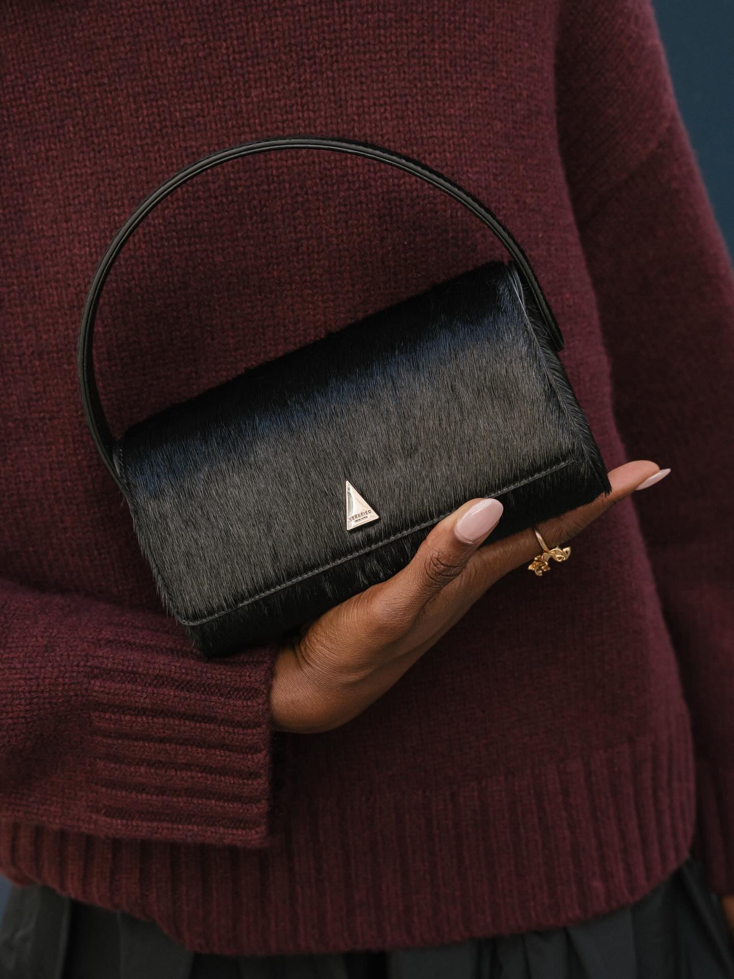 Foto de @emmanuellek_ con un jersey color burdeos sosteniendo un mini bolso negro con uñas rosas transparentes