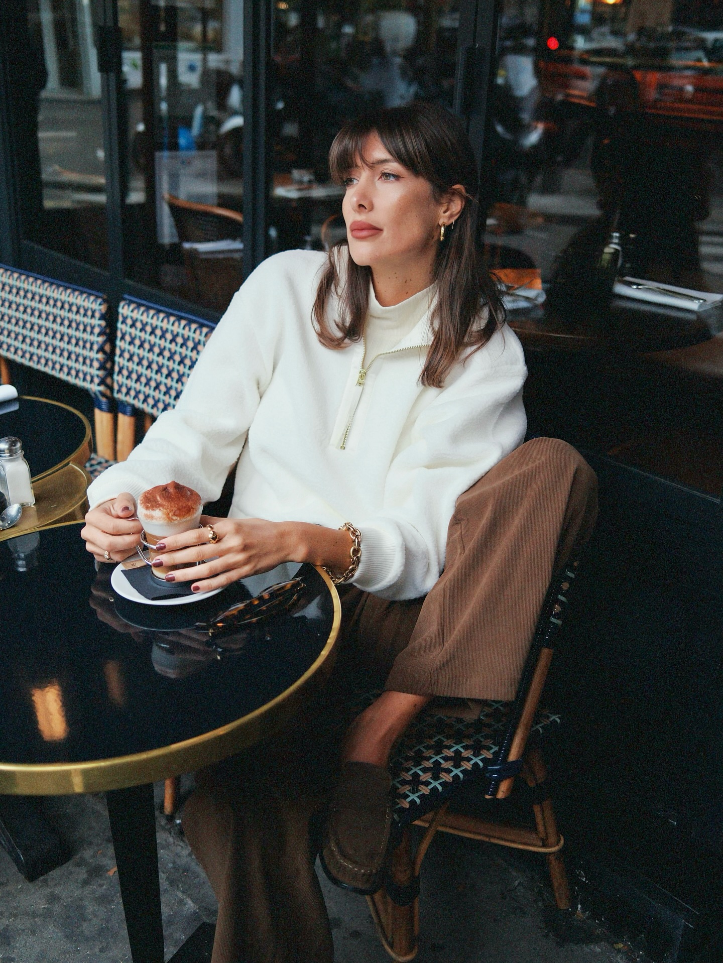 Una foto de @juliesfi sentada en un café francés con un jersey blanco