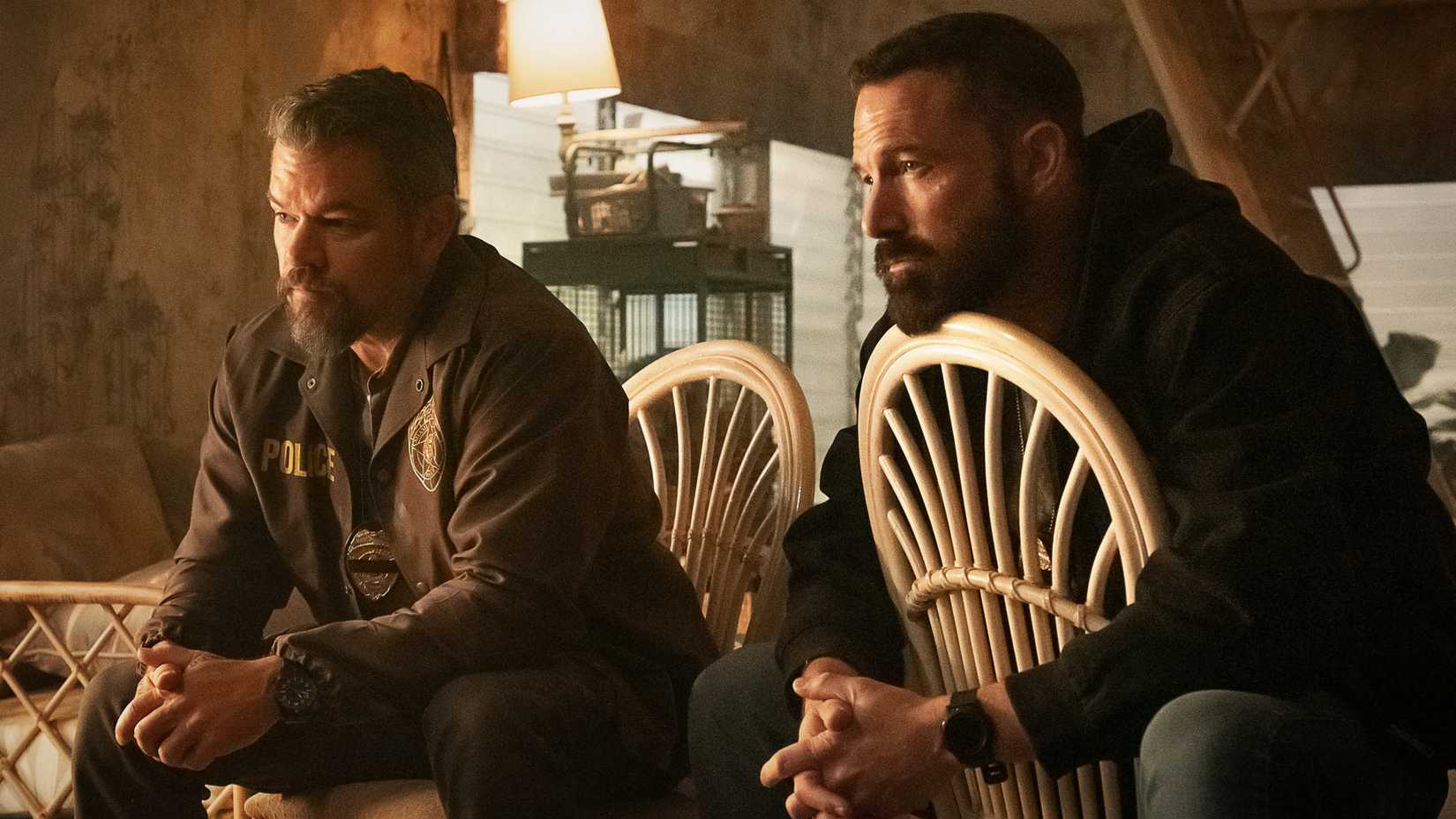 Ben Affleck y Matt Damon están sentados en sillas hablando con alguien fuera de la pantalla en The Rip.