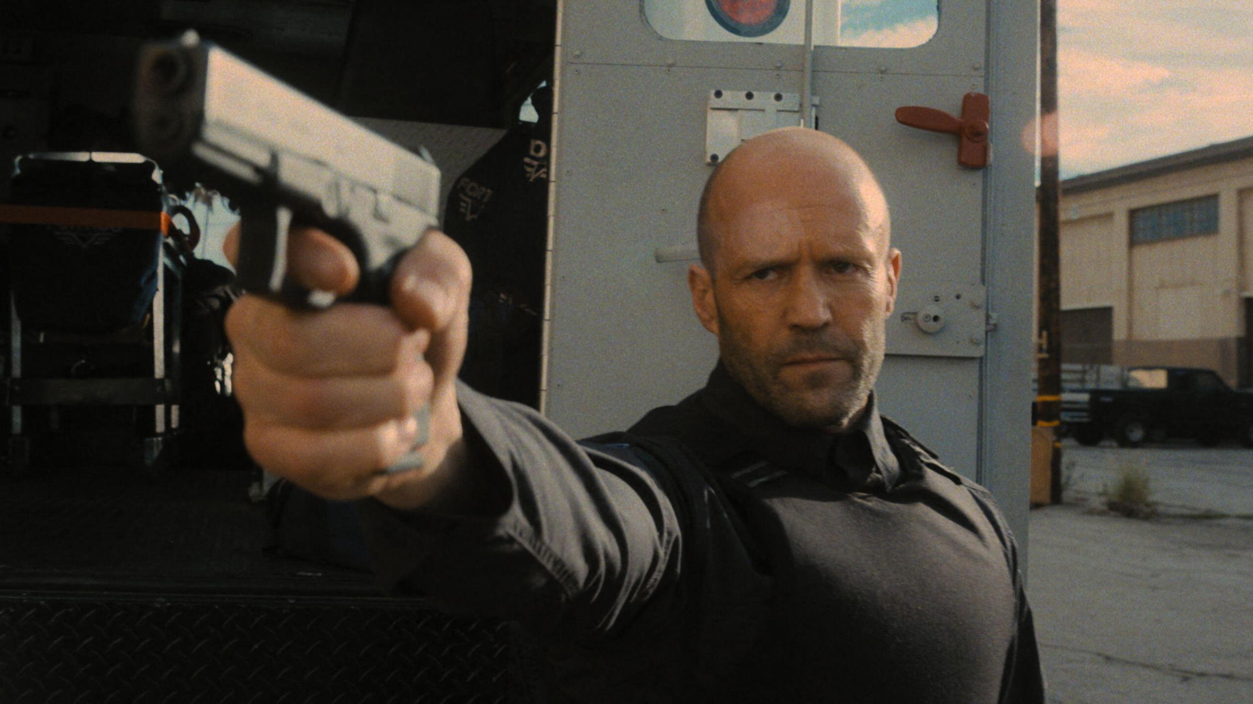 "h" (Jason Statham) Guy Ritchie "Ira del hombre"prepara una pistola en una escena de