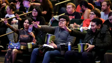 Los fanáticos de Netflix en Los Ángeles asisten a una proyección de Stranger Things, sentados entre el público con los brazos extendidos.