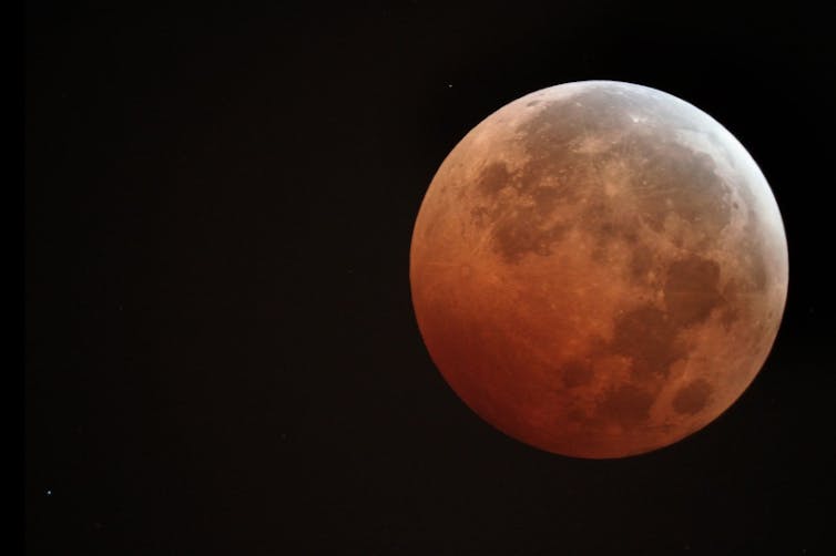 La luz del sol tiñe de naranja la luna llena durante un eclipse lunar.