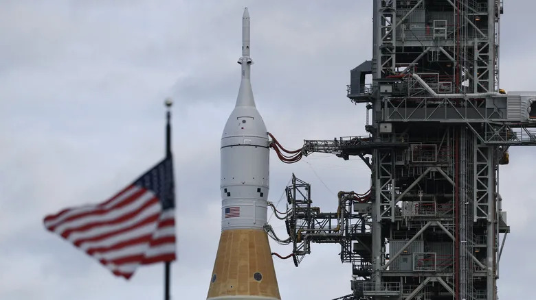 El cohete Artemis II de la NASA en el Centro Espacial Kennedy con la bandera estadounidense ondeando encima